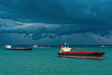 Oil/Chemical tankers anchored on outer anchorage in the Strait of Singapore under the stormy clouds.