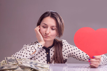 Concept: career vs personal life. Beautiful woman holding heart and cash as symbol of choice...