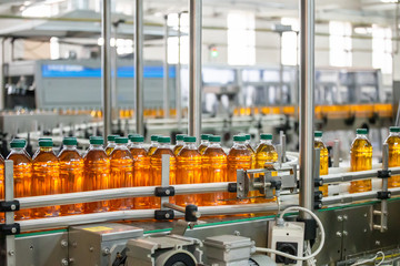 Plastic bottles with fresh organic juice on automatic conveyor belt or line in beverage factory or plant