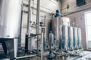 Stainless steel juice factory equipment, large reservoirs or tanks and pipes in modern plat....