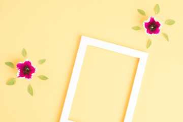 Beautiful pink flowers and blank frame on yellow background. Top view, copy space.