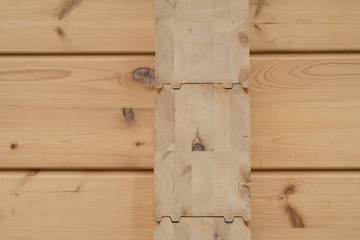 Details of a wooden house. The beams of the ceiling and the walls of the house of glued laminated timber. Summer day.