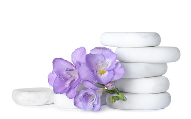 Stack of marble spa stones and fresh flowers isolated on white