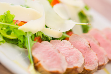 Pork medallions with parmesan, rocket and tomato