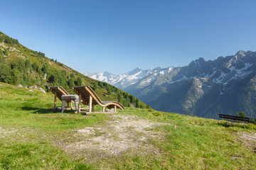Liegestühle aus Holz mit Aussicht über die Alpen