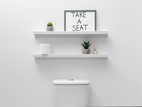 Toilet Bowl, Decor Elements And Funny Sign Near White Wall. Bathroom Interior