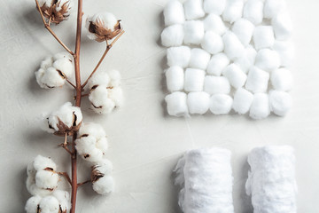 Flat lay composition with cotton balls, rolls and flowers on grey stone background