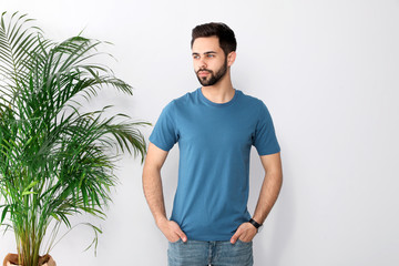 Young man in t-shirt near light wall. Mock up for design