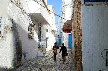 Two students go to school on the street of the old town of Sousse.