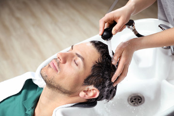 Obraz na płótnie Canvas Stylist washing client's hair at sink in beauty salon