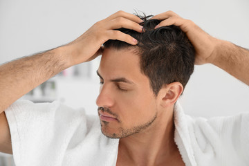 Handsome man applying hair conditioner in bathroom