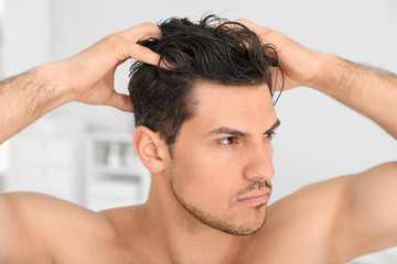 Handsome man applying hair conditioner in bathroom