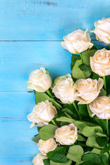 many white roses on a blue wooden background with a gift, a postcard to the day of the mother, Valentine's day or a woman's day. greeting card. place for text. top view
