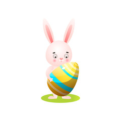 Cute easter rabbit on green grass with gold egg