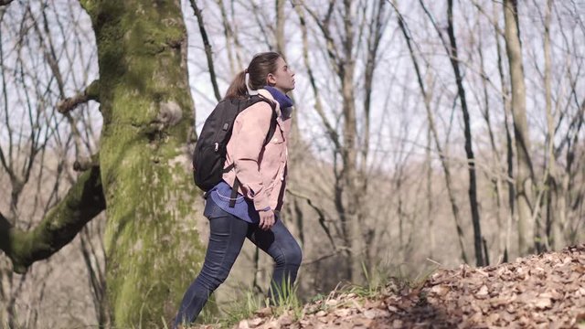 Girl traveler with a backpack travels in the forest