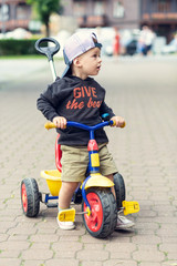 Boy on a three-wheeled bicycle in a cap with a visor. Shallow depth of field.