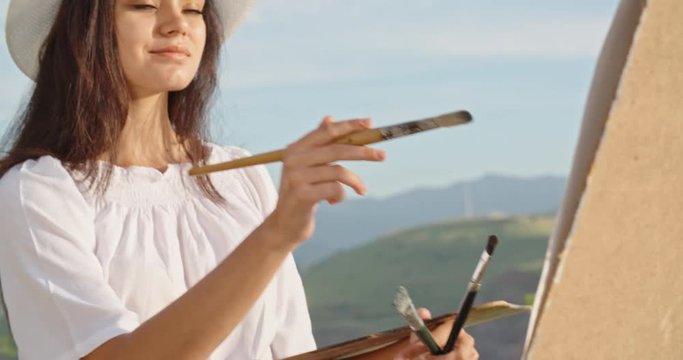 Caucasian female artist enjoying her time in mountains, creating a picture inspired by gorgeous view - hobby, recreational pursuit, inspirational landscape concept 4k footage
