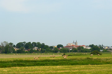 Fototapeta na wymiar Field with bales of hay with old polish town in the background