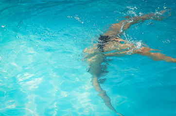 Young woman swimming underwater in swimming pool.