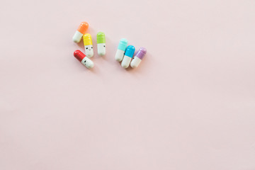 Funny multicolored capsule on a pastel paper pink background. Copyspace