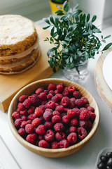 Ripe raspberries in a wooden plate on the table