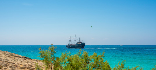  the ship sails from the rocky shore to the blue sea