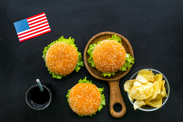 Burger, chips and usa flag for national american kitchen concept on black background top view