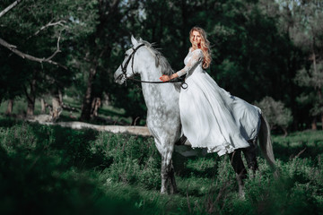 Fototapeta premium Beautiful and stunning bride, riding a horse in the nature