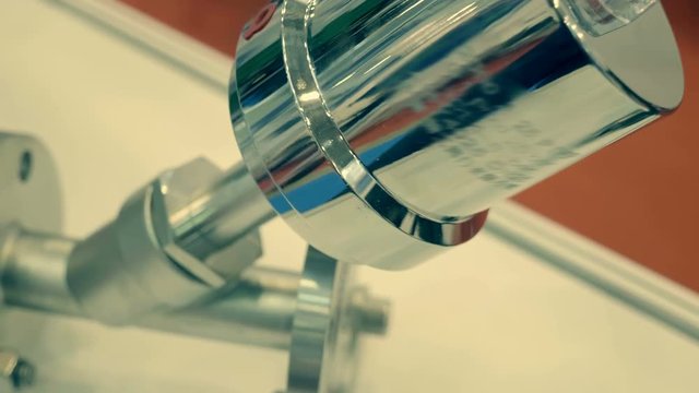 Shiny ball valves lie on a white surface. A new samples is presented for review at the exhibition. Shot in motion