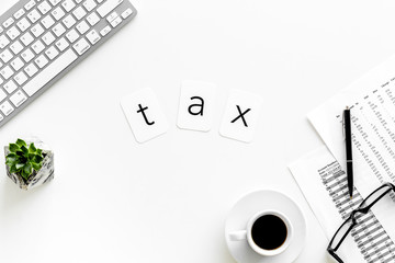 Tax copy on accountant work place with keyboard, coffee and glass on white desk background top view