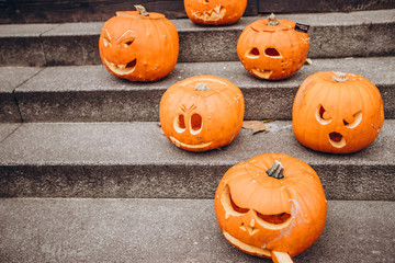 Pumpkin with a face stands on the street and decorates the street scaring passers-by people. pumpkin with a carved face in the twilight. Sinister atmosphere. Happy Halloween.