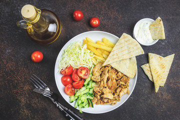 Greek gyros platter with french fries and vegetables.