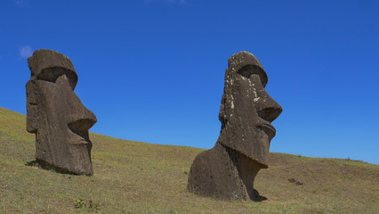 AERIAL: Scenic view of two sculptures with human faces on the remote island.