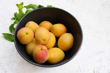Fresh summer sweet apricots in bowl on white stone table.