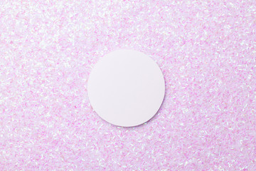 White sticker on the background of a brilliant rainbow background from a variety of small sequins.