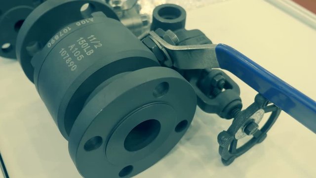 Black ball valves lie on a white surface. A new samples is presented for review at the exhibition. Shot in motion