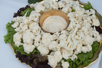 Fresh cauliflower with cheese sauce and salad leaves on table, close-up.