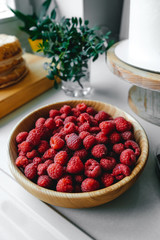 Ripe raspberries in a wooden plate on the table