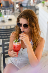 Young woman drinking cocktail in the summer restaurant terrace bar on vacation holiday