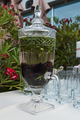 Fresh fruit and vegetable drink in a glass pitcher with tap, close-up