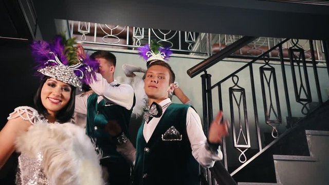 Theme party - Young people in stylish glistening retro clothes standing on the stairs and showing off their costumes