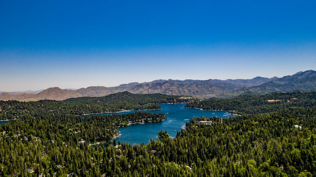 Aerial, quadcopter panorama of Lake Arrowhead in the San Bernardino Mountains, California on a sunny, clear day with blue sky, blue water, green pine trees and purple mountains