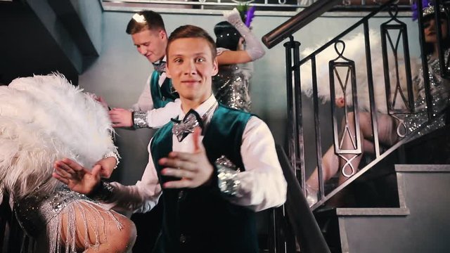 Theme party - Young people in stylish glistening retro clothes standing on the stairs and showing off their costumes and dancing