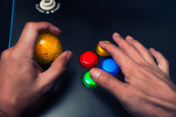 Arcade gamer holding a yellow bubble top joystick and playing on a four button layout arcade machine.