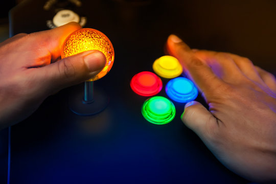 Lighted arcade bubble top joystick and buttons being played by retro gamer.