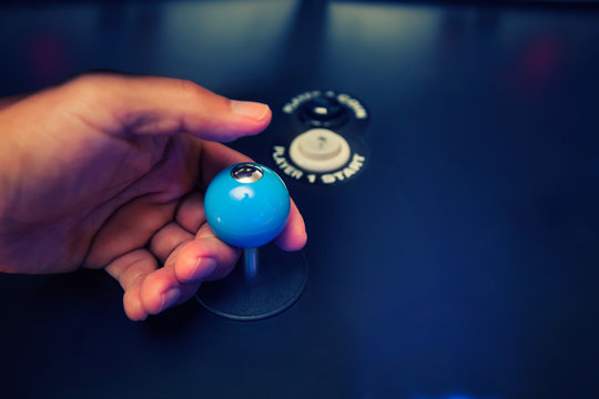 Hands of a video gamer holding a classic 4 way joystick with custom top fire modification and arcade buttons.