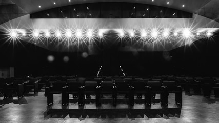 View towards empty audience seats at from stage with deliberate spotlights - monochrome