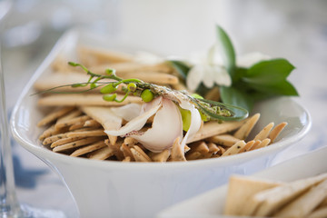White bowl of homemade crackers with fresh green shoots on top. 