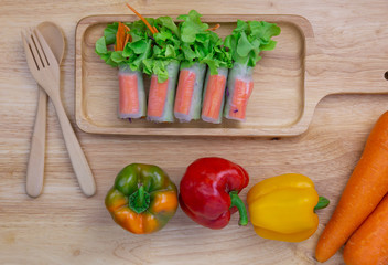 fresh vegetables salad and crab sticks are wrapped with noodle on wooden plate