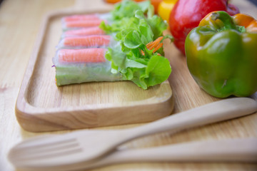 fresh vegetables salad and crab sticks are wrapped with noodle on wooden plate
